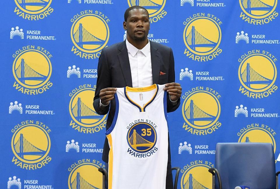 El estadounidense Kevin Durant muestra la camiseta de los Golden State Warriors durante una conferencia de prensa, el 7 de julio de 2016, en Oakland, Estados Unidos (GETTY/AFP/Archivos | Thearon W. Henderson)