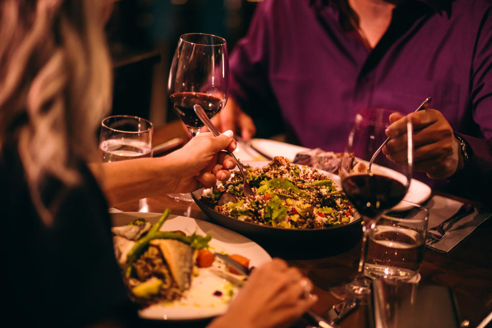 Couple on dinner date night eating healthy food with quinoa salad and drinking red wine