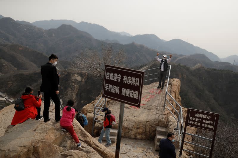 A man wearing a protective mask poses for a picture at the Great Wall in Badaling in Beijing