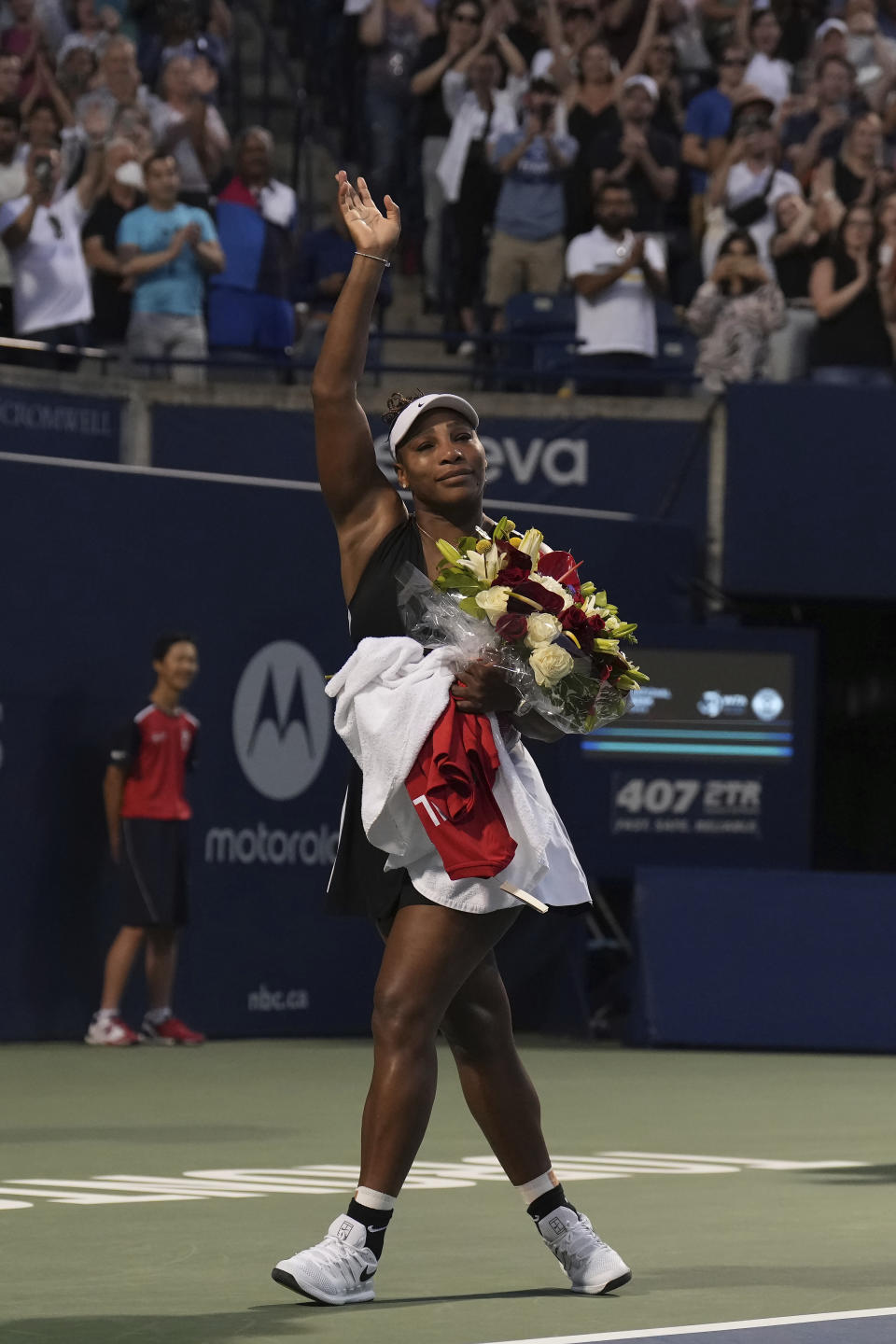 Serena Williams, of the United States, leaves the court carrying flowers and waving to fans after her loss to Belinda Bencic, of Switzerland, during the National Bank Open tennis tournament Wednesday, Aug. 10, 2022, in Toronto. (Chris Young/The Canadian Press via AP)