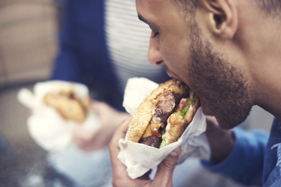 A man taking a bite of a cheeseburger.