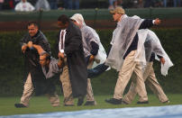 Security personnel carry a fan who ran onto the field from the stands and slid across the wet tarp during a rain delay of a game between the Chicago Cubs and the San Diego Padres on August 12, 2004 at Wrigley Field in Chicago, Illinois. The Padres defeated the Cubs 5-4 in 11 innings after two rain delays. (Photo by Jonathan Daniel/Getty Images)