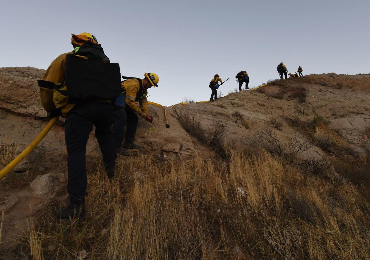 Firefighters climb the canyons to build a fire break during the Tick Fire in Agua Dulce near Santa Clarita, California on Oct. 25, 2019. Emergency services battled through the night to contain the fast-moving wildfire driven by high winds that was threatening to engulf thousands of buildings. Around 40,000 people were told to evacuate the area due to the Tick Fire.