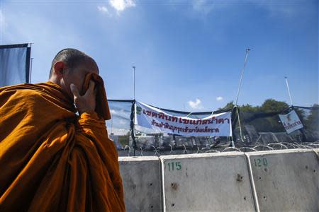 A Buddhist monk covers his face with wet handkerchief during clashes with police near government house in Bangkok December 1, 2013. REUTERS/Athit Perawongmetha