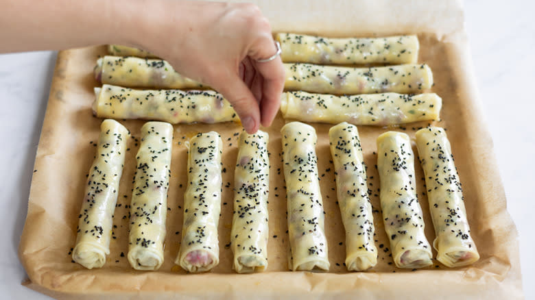 Hand sprinkling nigella seeds on filo pastries