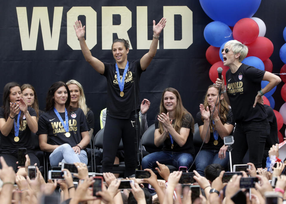 U.S. women's soccer team midfielder Megan Rapinoe, right, introduces teammate Carli Lloyd during a public rally held to celebrate the team's World Cup championship, Tuesday, July 7, 2015, in Los Angeles. This was the first U.S. stop for the team since beating Japan in the Women's World Cup final Sunday in Canada. (AP Photo/Jae C. Hong)