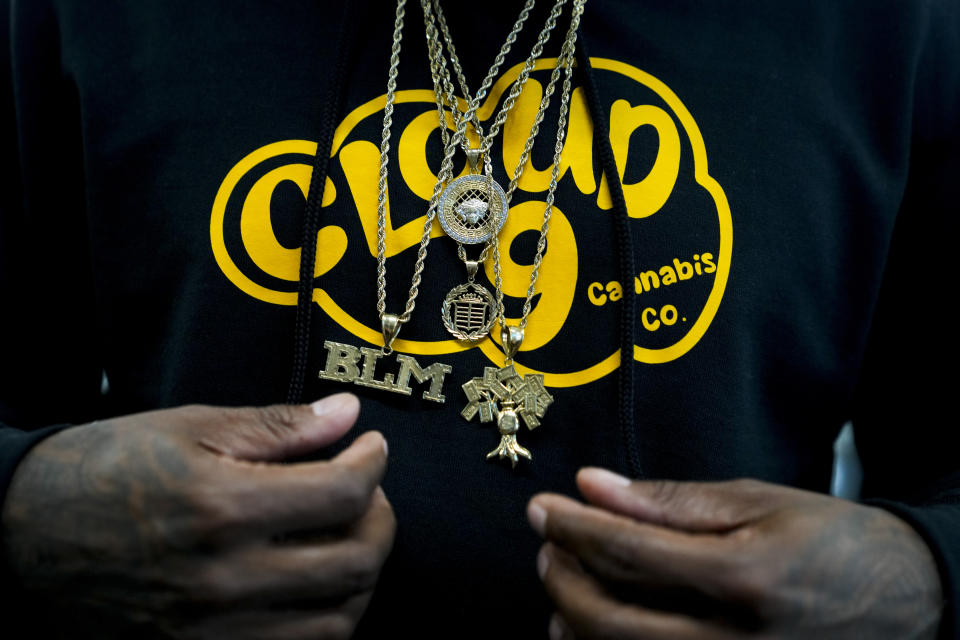 Cloud 9 Cannabis CEO and co-owner Sam Ward Jr. wears chains among over a custom hoodie, Saturday, April 13, 2024, in Arlington, Wash. The shop is one of the first dispensaries to open under the Washington Liquor and Cannabis Board's social equity program, established in efforts to remedy some of the disproportionate effects marijuana prohibition had on communities of color. (AP Photo/Lindsey Wasson)