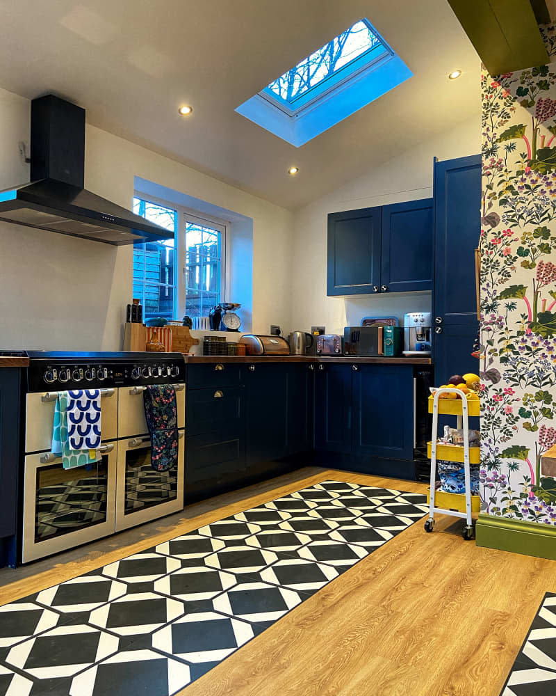 The kitchen features dark painted cabinets and black and white tile.