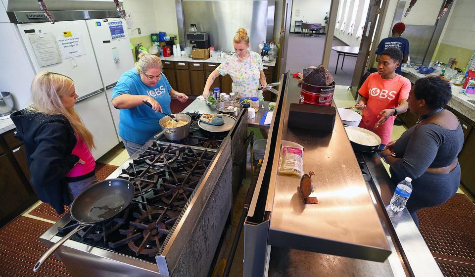 JOBS Executive Director Jennifer Herrick, left, and chef Jen Tidwell, right, help students cook during a class.