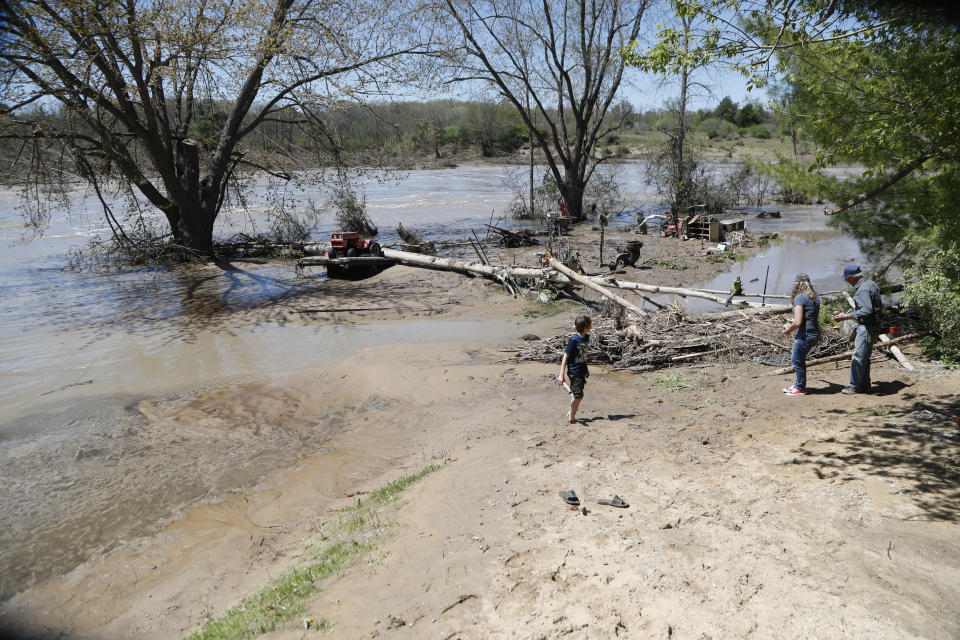 Members of Bob Yahrmarkt's family help pick up what is salvageable from his garage, Wednesday, May 20, 2020, in Edenville, Mich. Some people living along two mid-Michigan lakes and parts of a river have been evacuated following several days of heavy rain that produced flooding and put pressure on dams in the area returned to the area to survey the damage. (AP Photo/Carlos Osorio)