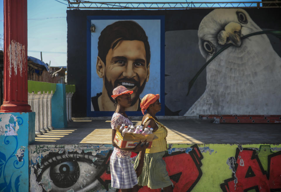 Street vendors walk past a mural of Argentine football star Lionel Messi and a peace dove in La Saline district of Port-au-Prince, Haiti, Tuesday, Jan. 24, 2023. An average of four people are kidnapped a day in Haiti, according to U.N. estimates. The U.N. clocked nearly 2,200 murders in 2022, doubling from the year before. (AP Photo/Odelyn Joseph)