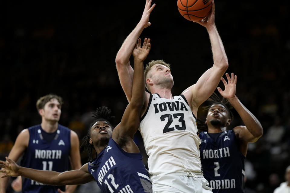 Iowa forward Ben Krikke (23) drives to the basket between North Florida guard Jaylen Smith (12) and guard Chaz Lanier (2) during the second half of an NCAA college basketball game, Wednesday, Nov. 29, 2023, in Iowa City, Iowa. (AP Photo/Charlie Neibergall)