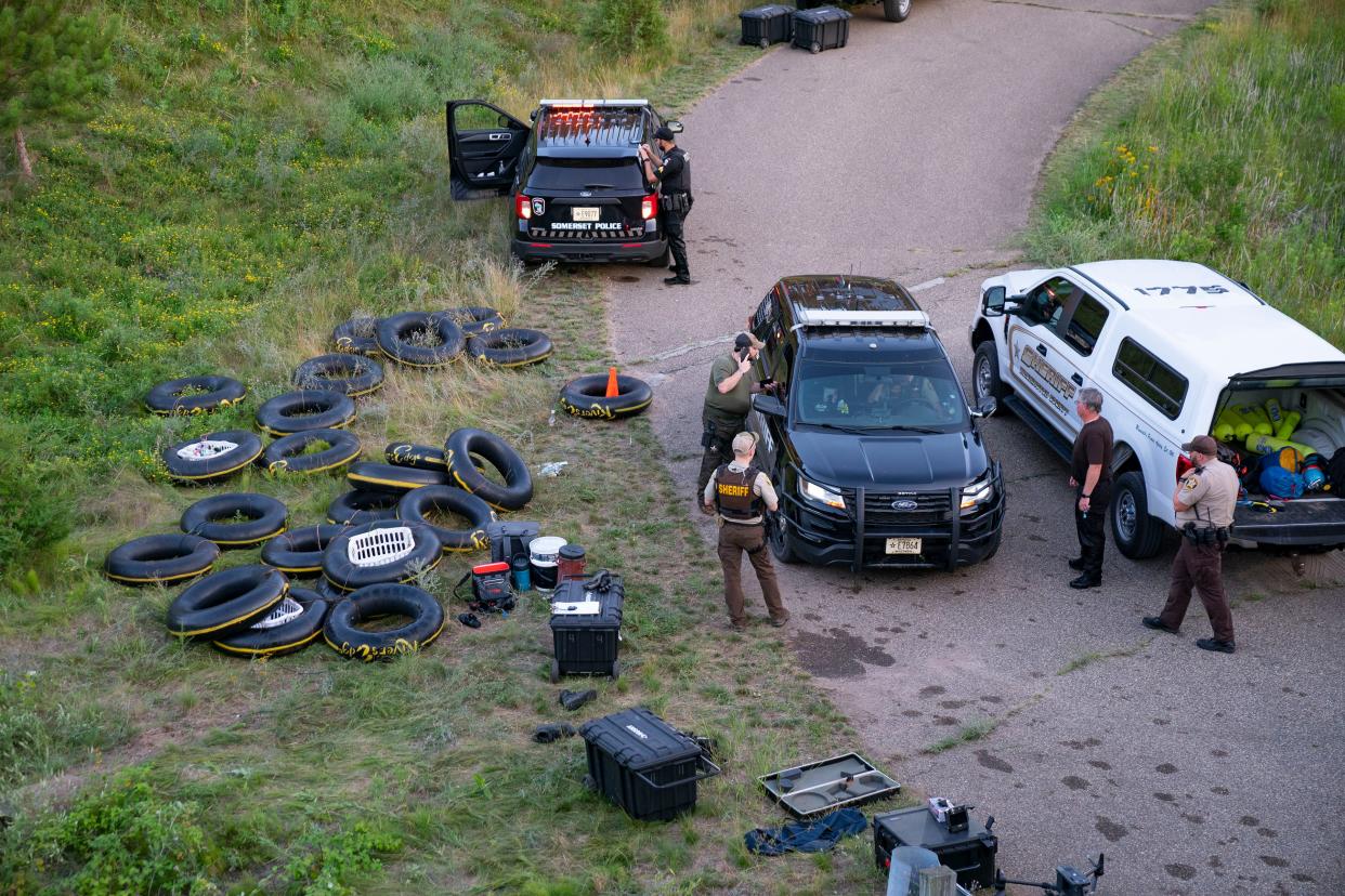 Tubes sit on the bank of the Apple River while Water Recovery authorities comb the area with metal detectors after five people were stabbed while tubing down the river Saturday, July 30, 2022, in Somerset, Wisconsin.