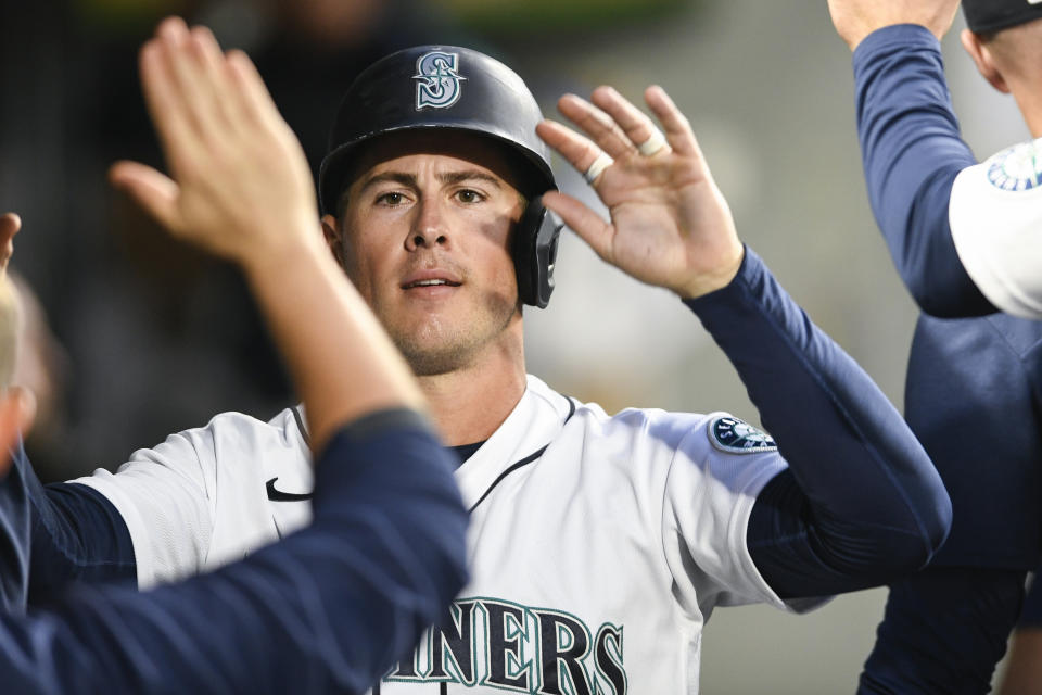 Seattle Mariners' Dylan Moore high fives his teammates in the dugout after scoring a run off of Eugenio Suarez' double against the Texas Rangers during the first inning of a baseball game, Wednesday, Sept. 28, 2022, in Seattle. (AP Photo/Caean Couto)