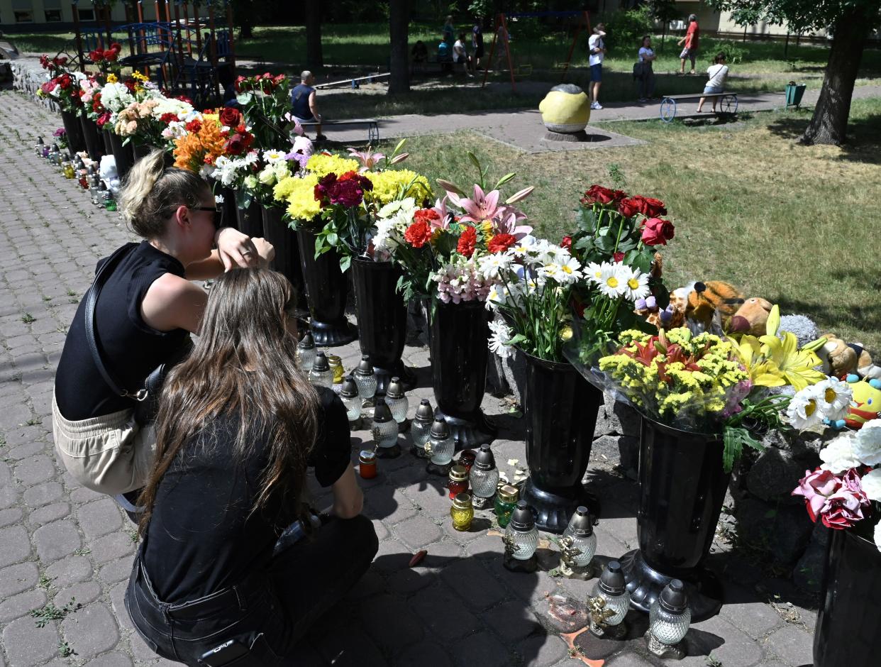 People lay flowers and children toys next to destroyed Amstor mall in Kremenchuk, on June 28, 2022, one day after it was hit by a Russian missile strike according to Ukrainian authorities. 