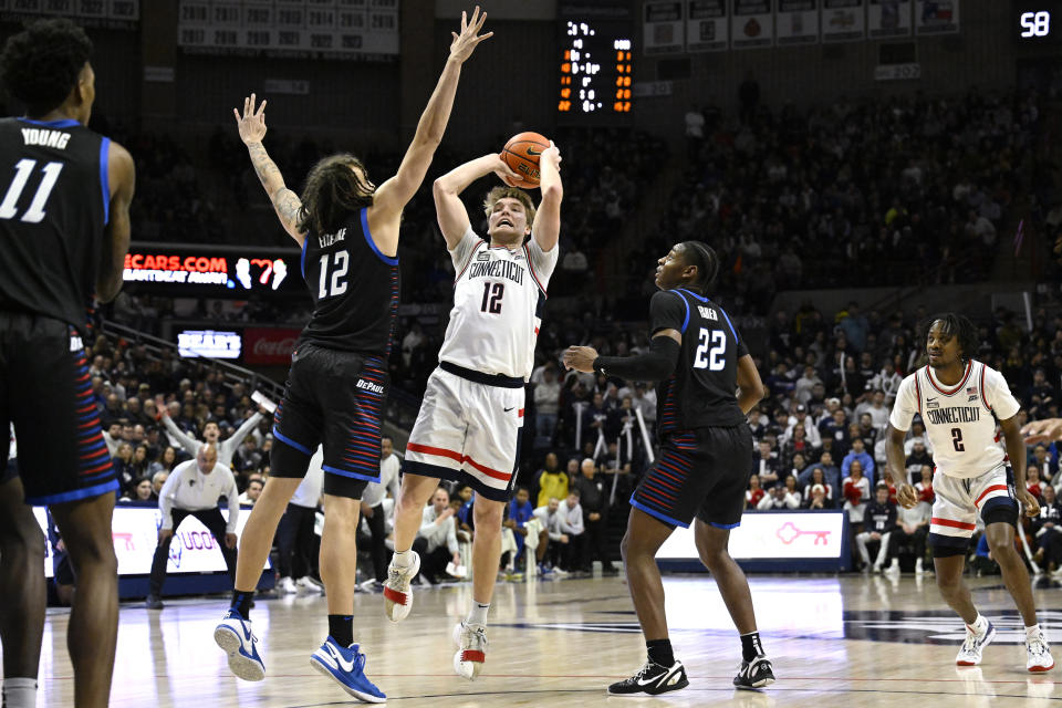 UConn guard Cam Spencer (12) shoots over DePaul forward Mac Etienne (12) as DePaul guard Elijah Fisher (22) defends in the second half of an NCAA college basketball game, Tuesday, Jan. 2, 2024, in Storrs, Conn. (AP Photo/Jessica Hill)