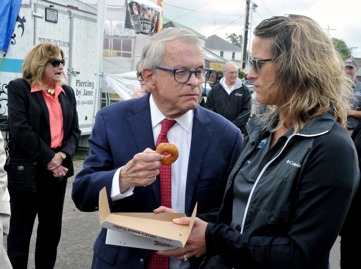 Gov. Mike DeWine accepts a Lerch's Donut from Diane Johnson at the Wayne County Fair on Tuesday, Sept. 13, 2022.