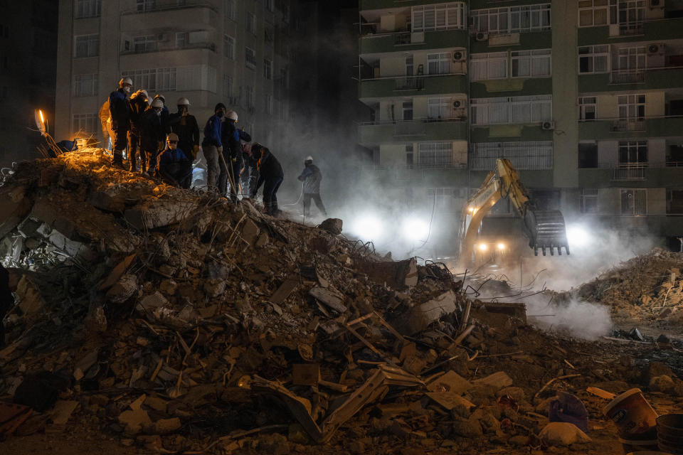 Rescue workers search for bodies and earthquake survivors on a collapsed building in Adana, southeastern Turkey, Friday, Feb. 10, 2023. Some 12,000 buildings in Turkey have either collapsed or sustained serious damage, according to Turkey's minister of environment and urban planning, Murat Kurum.(AP Photo/Bernat Armangue)