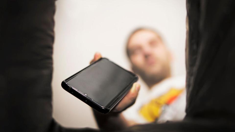 Un joven metiendo su teléfono inteligente en una caja