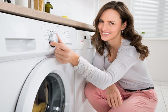 A woman adjusts settings on a washing machine.