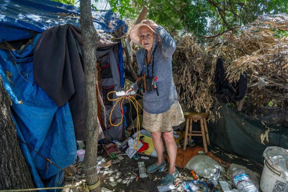 Carol Dutcher, 60, holds a lighting fixture as she tries to decide what belongings to save during a sweep after one of her structures was bulldozed in a homeless encampment in Rio Linda on Monday. Dutcher said she has lived at the site for four years. “They don’t care that they destroyed my home and I have no where to go or place to sleep tonight,” she said in tears. “Could you move your whole house in two days, four days…I don’t think anybody could.”