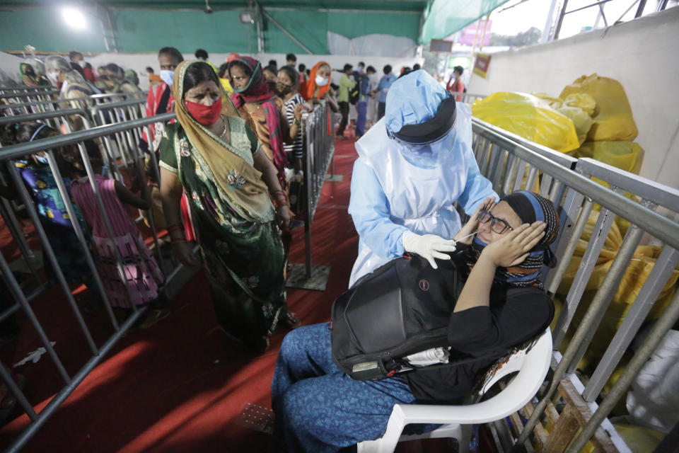 An Indian woman reacts as a health worker takes a nasal swab sample to test for COVID-19 at a facility erected at a railway station to screen people coming from outside the city, in Ahmedabad, India, Friday, Sept. 18, 2020. India's coronavirus cases jumped by another 96,424 in the past 24 hours, showing little sign of leveling. India is expected to have the highest number of confirmed cases within weeks, surpassing the United States, where more than 6.67 million people have been infected. (AP Photo/Ajit Solanki)