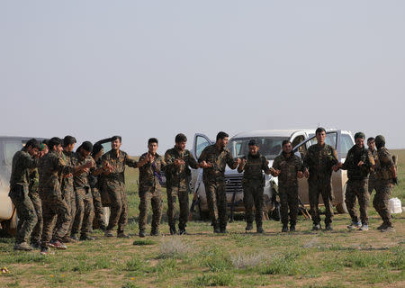 Fighters from the Syrian Democratic Forces (SDF) dance near the village of Baghouz, Deir Al Zor province, Syria February 25, 2019. REUTERS/Rodi Said