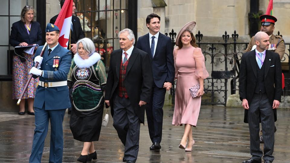 a procession of people carry the Canadian flag in the rain