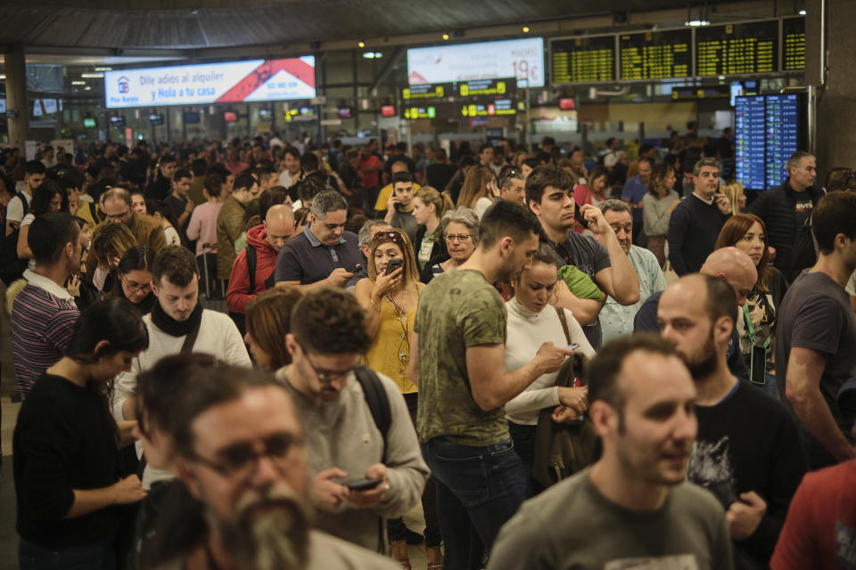 Passengers stand and queue in the airport in Santa Cruz de Tenerife, Spain, Sunday, Feb. 23, 2020. Flights leaving Tenerife have been affected after storms of red sand from Africa's Saharan desert hit the Canary Islands. (AP Photo/Andres Gutierrez)