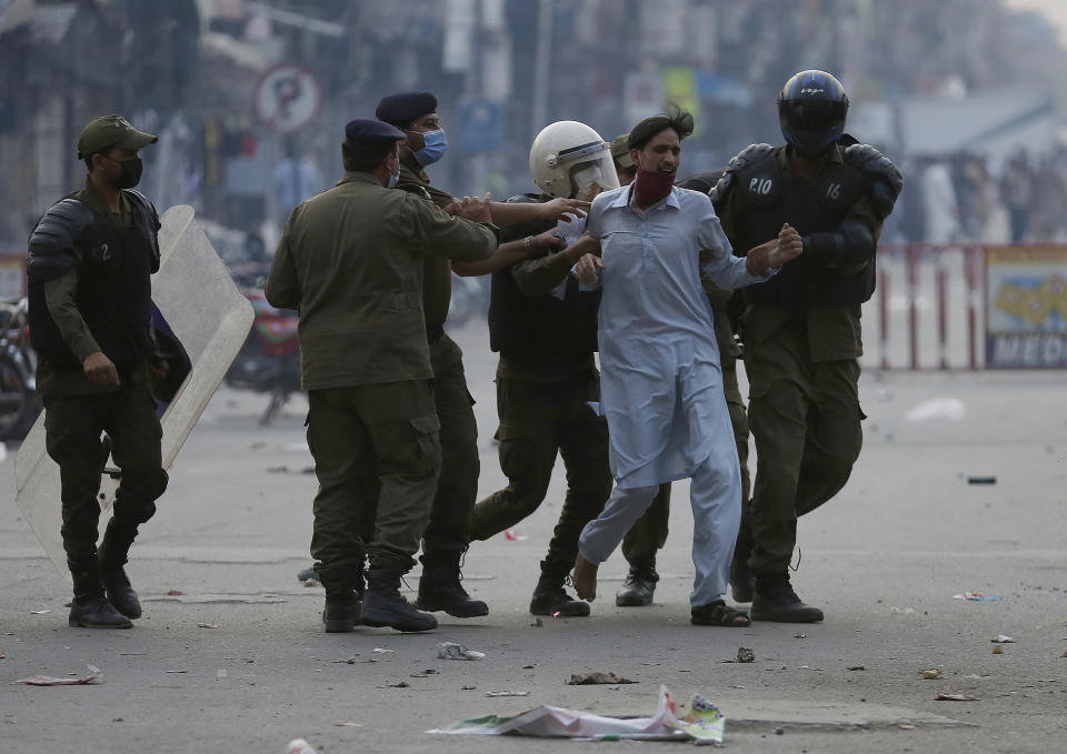 Police officers take into custody a supporter of Tehreek-e-Labiak Pakistan, a radical Islamist political party, at a protest against the arrest of their leader Saad Rizvi, in Lahore, Pakistan, Monday, April 12, 2021. Pakistan police arrested Rizvi a day after he threatened the government with protests if it did not expel France's ambassador over depictions of Islam's Prophet Muhammad. (AP Photo/K.M. Chaudary)