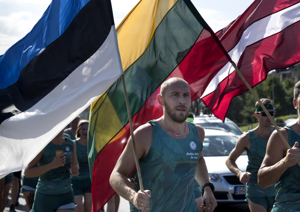 Lithuanian people take part in a traditional relay race Vilnius-Riga-Tallinn dedicated to the 30th anniversary of the Baltic Way at the Cathedral Square in Vilnius, Lithuania, Friday,Aug. 23, 2019. Estonia’s prime minister says one should never forget the 1989 “Baltic Way” in which nearly 2 million people of then-Soviet Lithuania, Latvia and Estonia formed a human chain more than 600 kilometers (370 miles) long to protest Soviet occupation. (AP Photo/Mindaugas Kulbis)