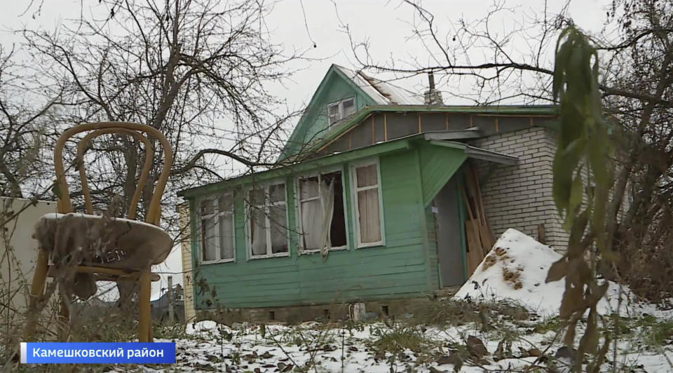 TV news footage still of green wooden house.