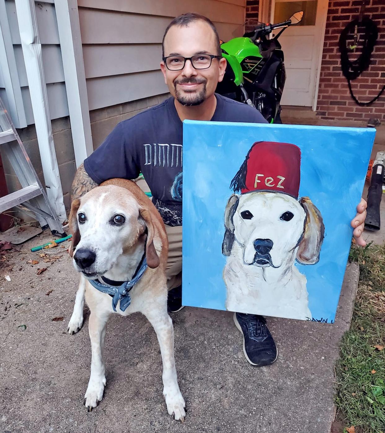 Man holding a dog painting next to a dog for cheddar paws dog art