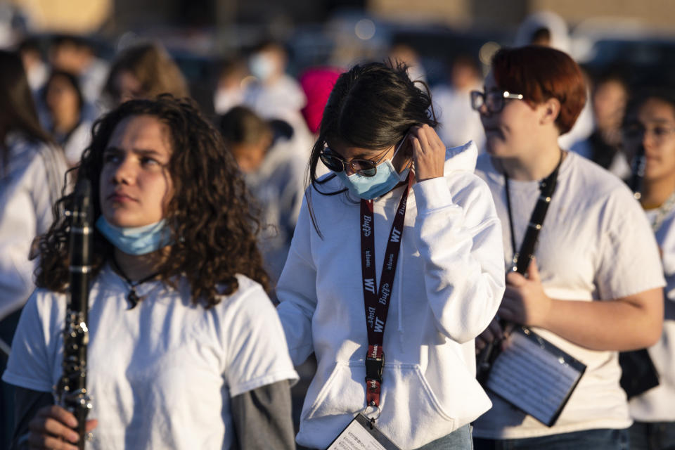 Marissa Equiniones, 17, center, puts on her face mask between drills during marching band practice Thursday, Sept. 23, 2021 in Odessa, Texas. (Eli Hartman/Odessa American via AP)