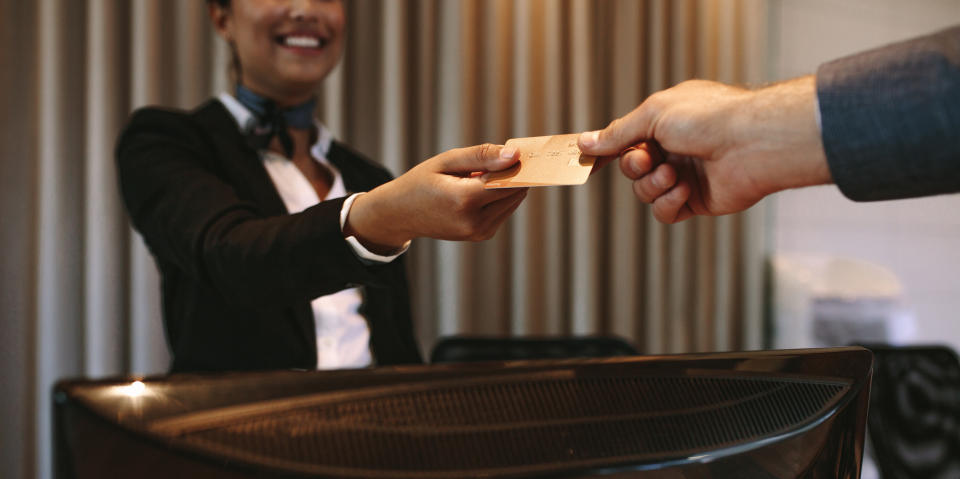 Person at a reception desk handing a key card to a guest