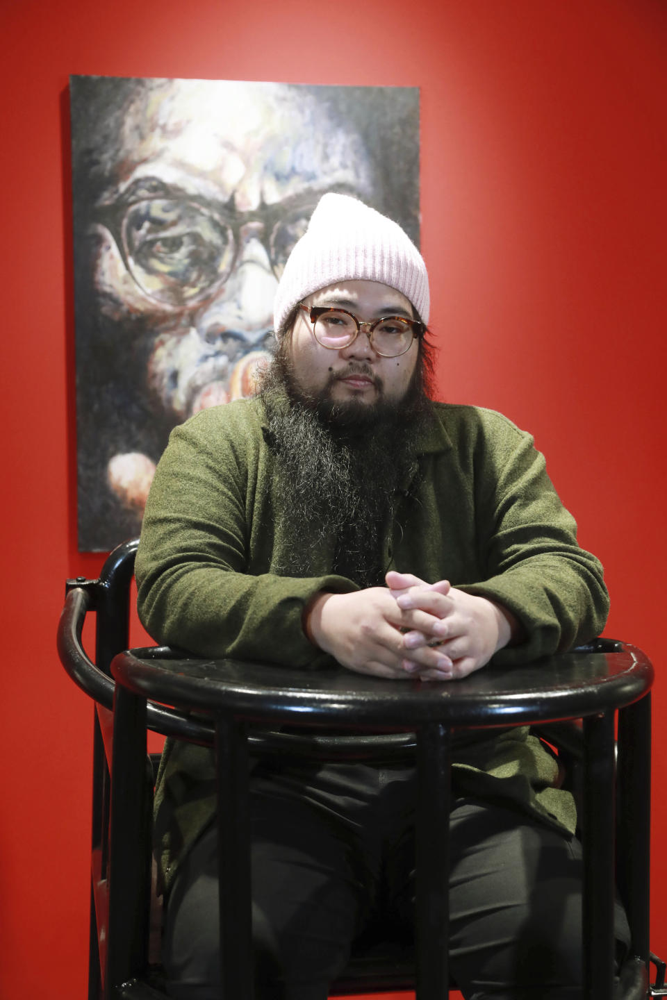 Artist Badiucao sits in a torture chair, part of his exhibition in the Santa Giulia Museum, in Brescia, Saturday, Nov. 13, 2021. A provocative exhibit by dissident Chinese artist Badiucao opened Saturday in the industrial northern Italian city of Brescia despite pressure from the Chinese embassy in Rome to cancel it. A letter from the embassy included veiled economic threats, noting Italy’s trade with China, in a bid to prevent the first solo exhibit by Badiucao — the pseudonym used by the artist whose work takes aim at China's policies and human rights record. During the exhibit’s opening days, Badiucao will sit in a torture chair and read from a diary shared with him by a resident of Wuhan, the Chinese city where the coronavirus was first detected. (AP Photo/Felice Calabro')