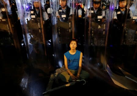 Demonstrator sits down in front of riot police during a demonstration to demand authorities scrap a proposed extradition bill with China, in Hong Kong