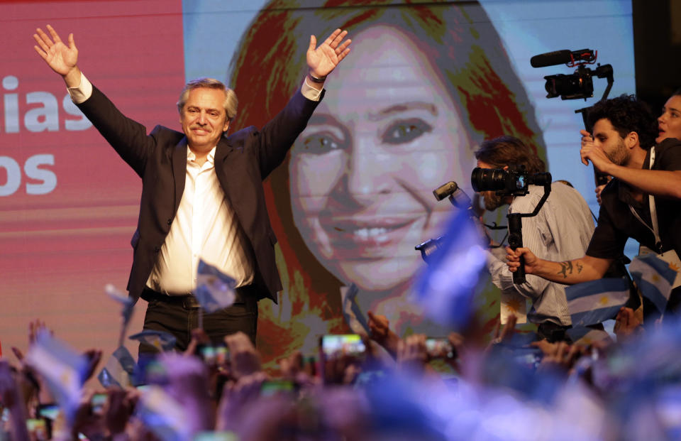 Peronist presidential candidate Alberto Fernández waves to supporters in front of a large image of his running mate, former President Cristina Fernández, after incumbent President Mauricio Macri conceded defeat at the end of election day in Buenos Aires, Argentina, Sunday, Oct. 27, 2019. (AP Photo/Daniel Jayo)