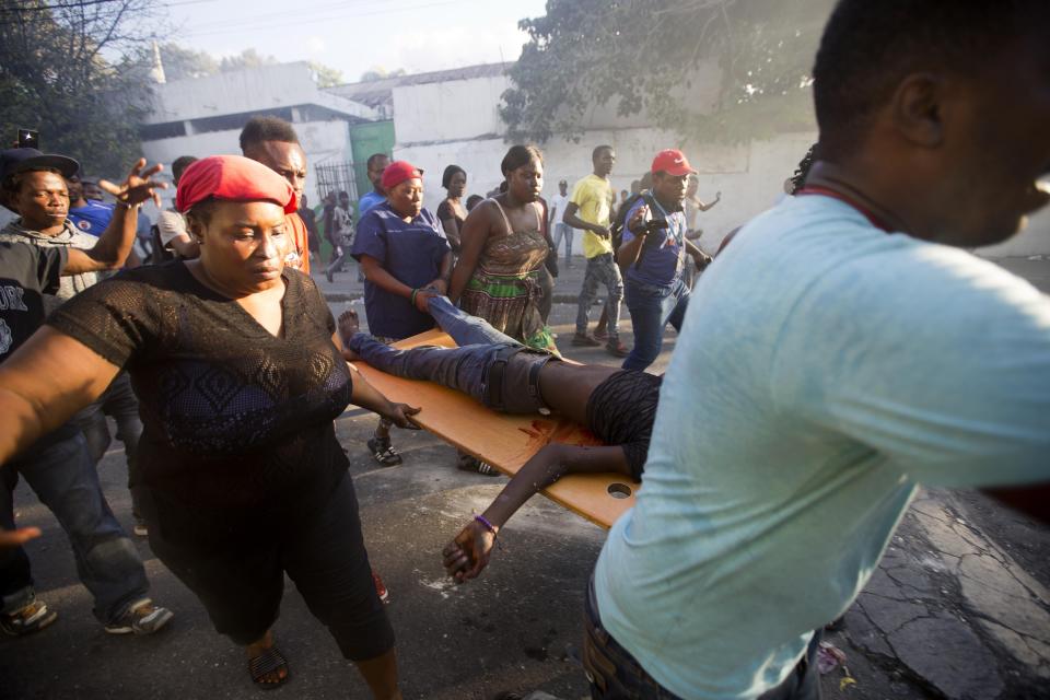 Demonstrators carry the body of a person killed during the violent clashes between the police and demonstrators near the national palace, during a protest to demand the resignation of President Jovenel Moise and demanding to know how Petro Caribe funds have been used by the current and past administrations, in Port-au-Prince, Haiti, Saturday, Feb. 9, 2019. Much of the financial support to help Haiti rebuild after the 2010 earthquake comes from Venezuela's Petro Caribe fund, a 2005 pact that gives suppliers below-market financing for oil and is under the control of the central government. (AP Photo/Dieu Nalio Chery)