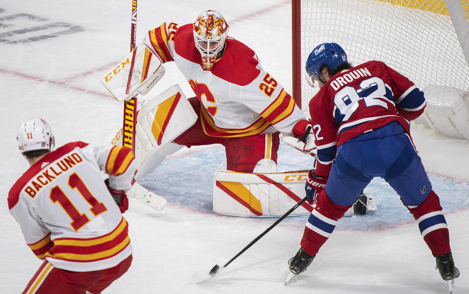 Montreal Canadiens' Jonathan Drouin (92) moves in on Calgary Flames goaltender Jacob Markstrom as Flames' Mikael Backlund defends during second-period NHL hockey game action in Montreal, Saturday, Jan. 30, 2021. (Graham Hughes/The Canadian Press via AP)