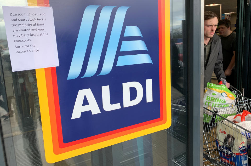 A man pushes a shopping trolley past a sign warning customers of product shortages.