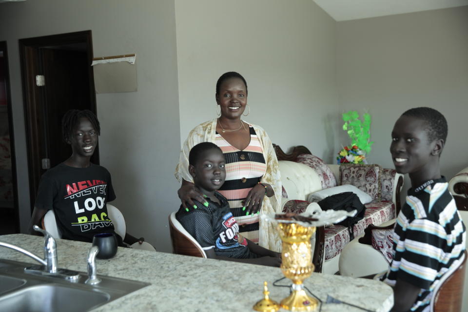 Achut Deng poses for a photo at her home in Sioux Falls, S.D., on Sept. 17, 2022 with her sons, from left, Deng Kuek, Kuek Kuek and Mayom Meyon. (AP Photo/Stephen Groves)