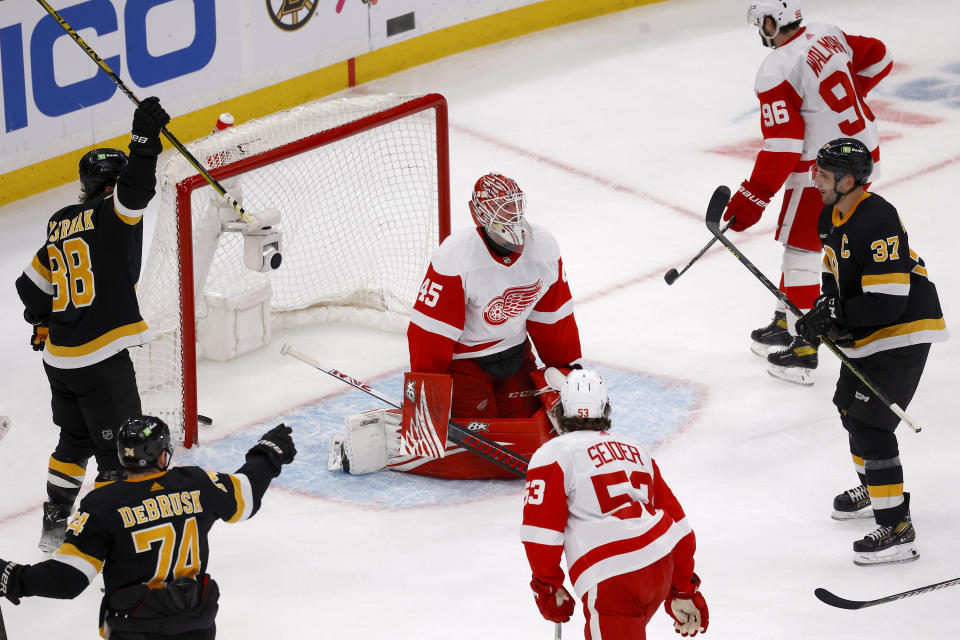 Boston Bruins right wing David Pastrnak (88) and left wing Jake DeBrusk (74) celebrate after Patrice Bergeron (37) scored a goal past Detroit Red Wings goaltender Magnus Hellberg (45) during the second period of an NHL hockey game, Saturday, March 11, 2023, in Boston. (AP Photo/Mary Schwalm)