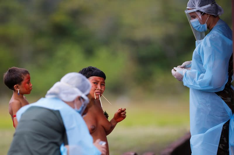 A member of Brazilian Armed Forces medical team examines a woman from the indigenous Yanomami ethnic group at the Surucucu region in the municipality of Alto Alegre