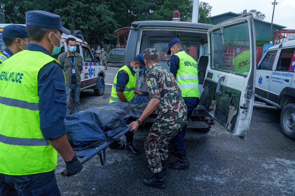 Nepalese army officials shift the dead body of a plane crash victim to an ambulance at an airport in Kathmandu, Nepal, Monday, May 30, 2022. 