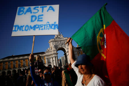 A woman holds a poster saying "enough incompetence" during a demonstration in a tribute to the victims of the deadly fires in Portugal, in Praca do Comercio square, downtown Lisbon, Portugal October 21, 2017. REUTERS/Pedro Nunes
