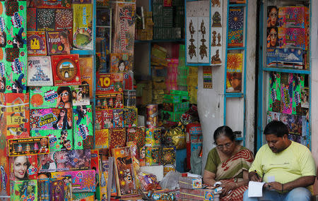 A woman and her son sit at their firecracker shop in the old quarters of Delhi, India, October 17, 2018. REUTERS/Adnan Abidi