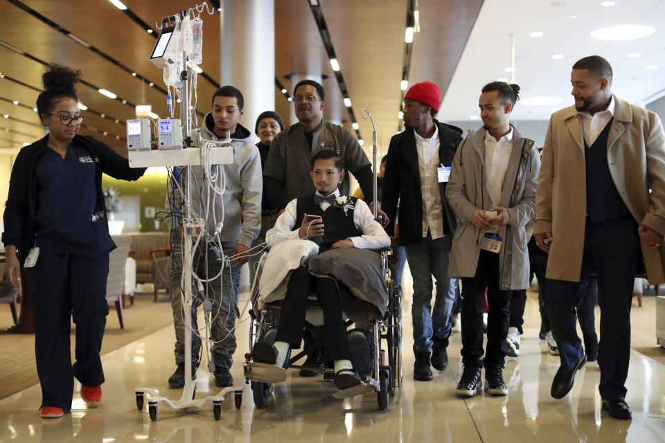 In this Wednesday, Nov. 27, 2019 photo, Javier Rodriguez arrives with family and his medical team for his wedding to Crystal Cuevas at the University of Chicago Medical Center for Care and Discovery in Chicago. Rodriguez, 23, who received two heart transplants as a teenager died in hospice care, days after he married his high school sweetheart, his new bride said. (Brian Cassella/Chicago Tribune via AP)