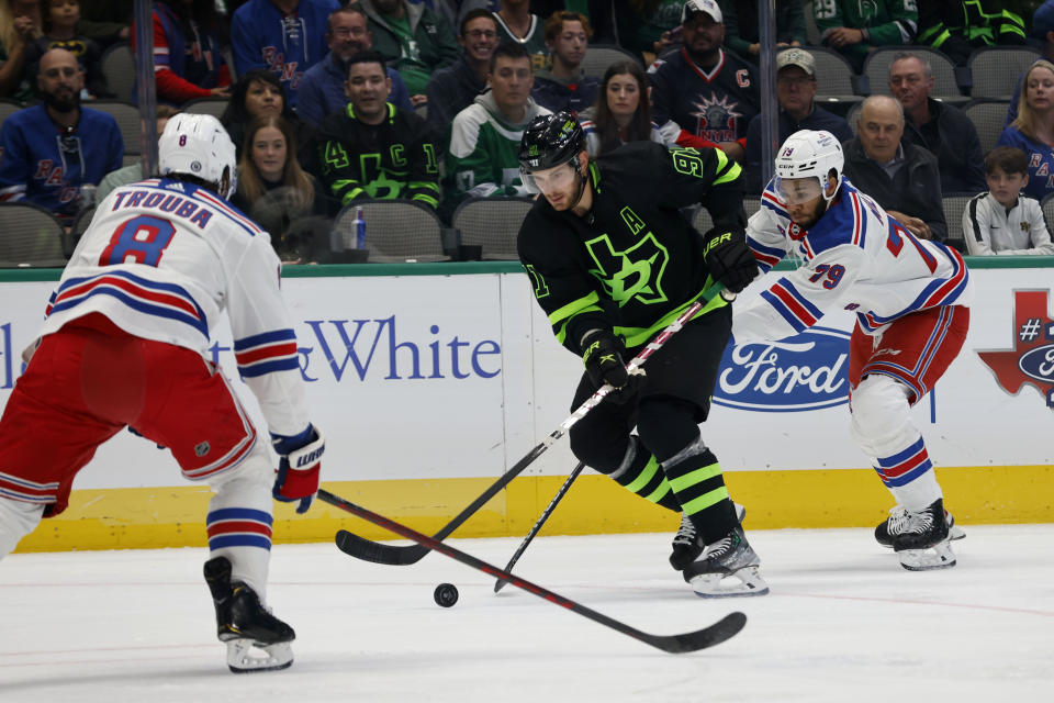 Dallas Stars center Tyler Seguin (91) tries to get the puck past New York Rangers defenseman Jacob Trouba (8) and defenseman K'Andre Miller (79) during the first period of an NHL hockey game in Dallas, Saturday, Oct. 29, 2022. (AP Photo/Michael Ainsworth)