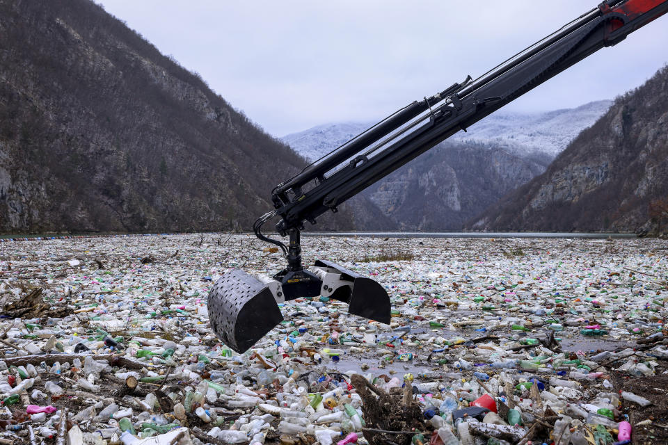 A crane moves to collect waste floating in the Drina river near Visegrad, Bosnia, Wednesday, Jan. 10, 2024. Tons of waste dumped in poorly regulated riverside landfills or directly into the rivers across three Western Balkan countries end up accumulating during high water season in winter and spring, behind a trash barrier in the Drina River in eastern Bosnia. (AP Photo/Armin Durgut)
